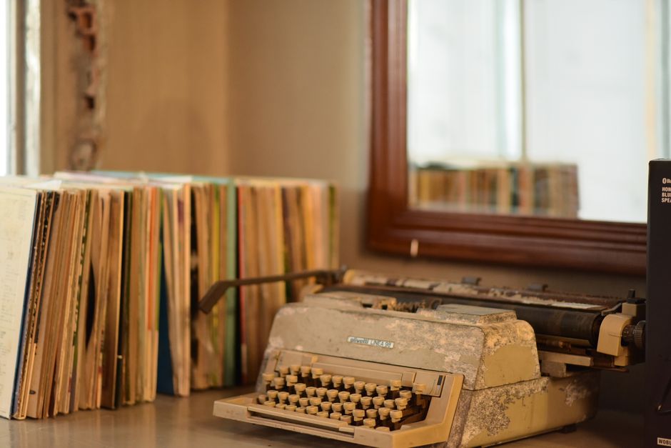A rustic typewriter beside stacked books reflects nostalgic charm in a vintage setting.